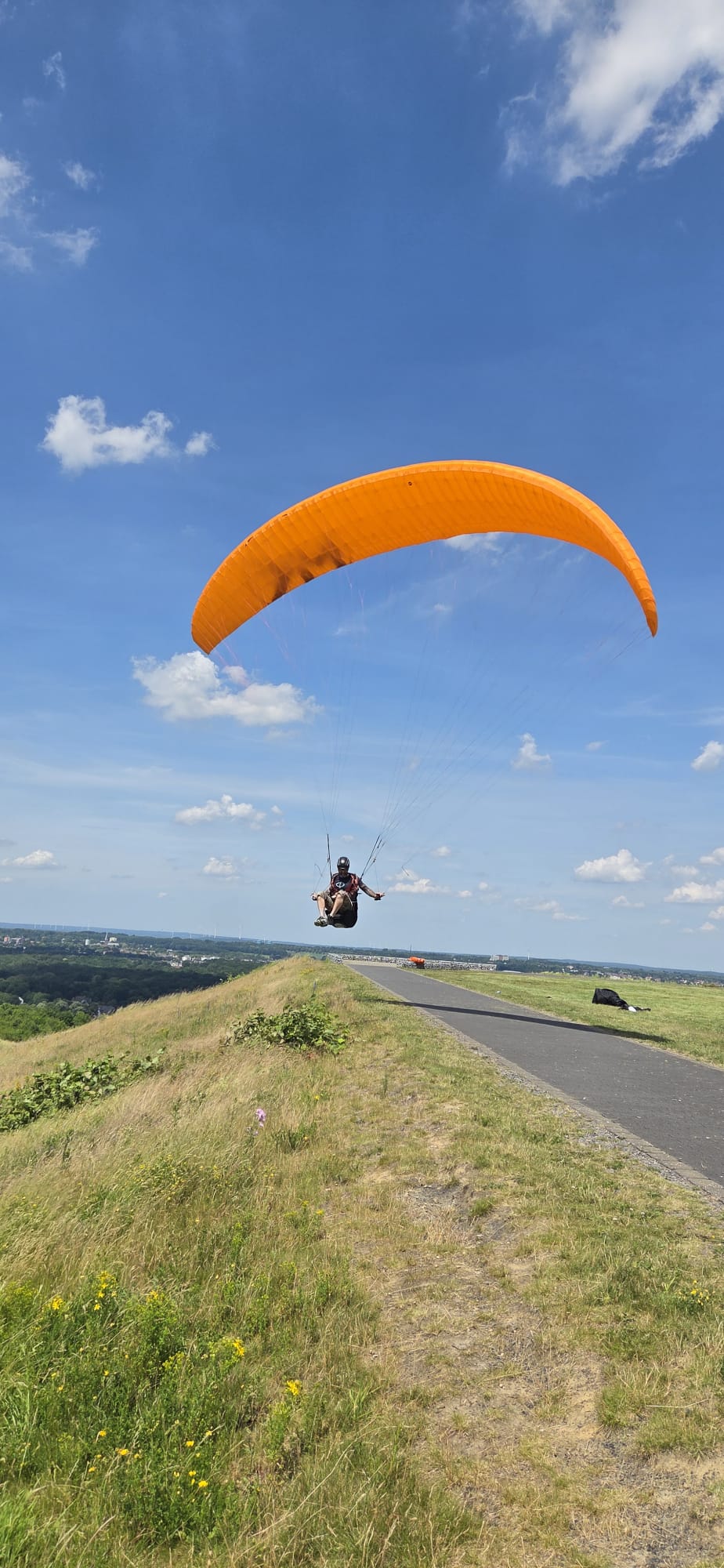 Pilot über der Halde im Ruhrgebiet mit orangem Schirm